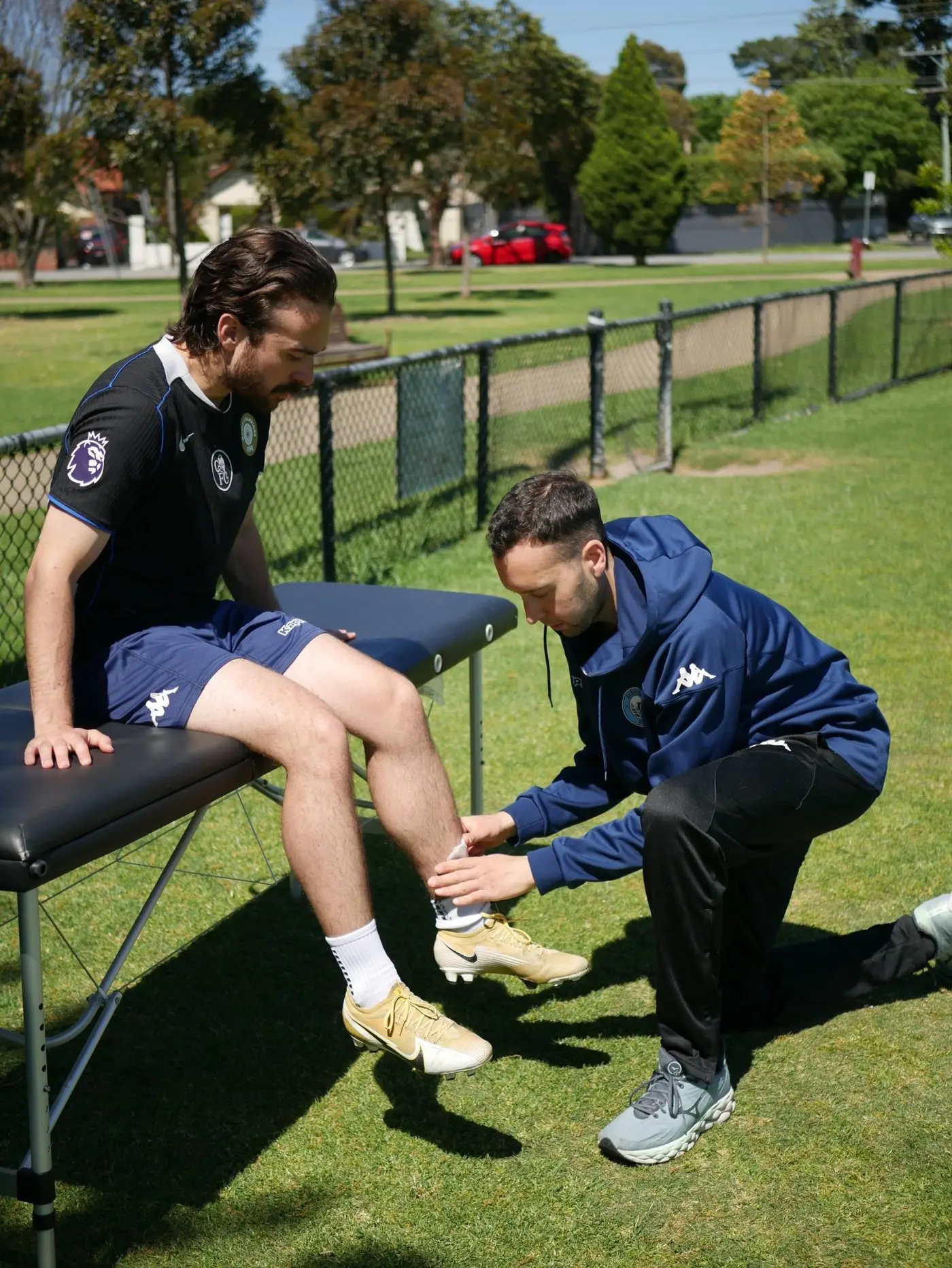 Jake taping a footballer's ankle beside a treatment table
