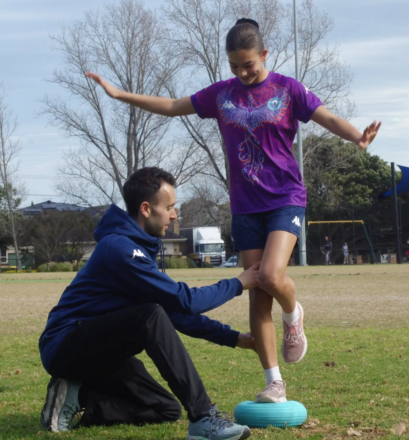 Player doing a single-leg balance exercise while Jake supports her knee