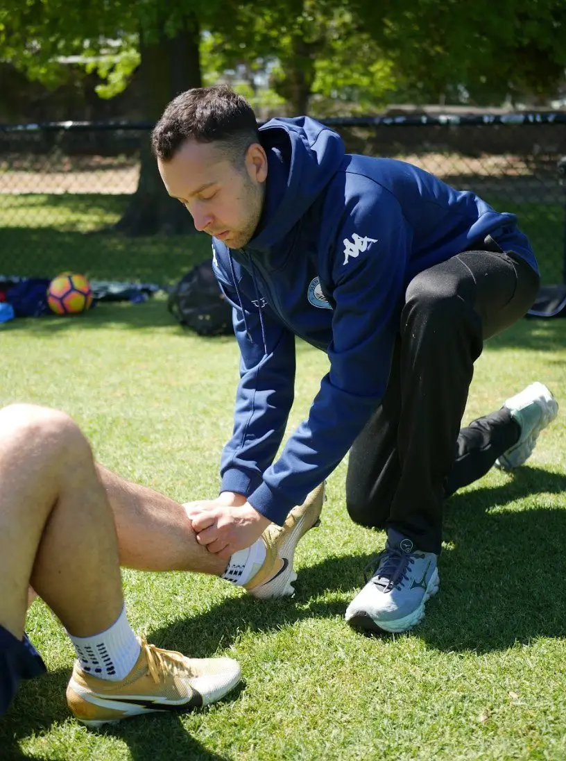Jake assessing a footballer's lower leg on the field